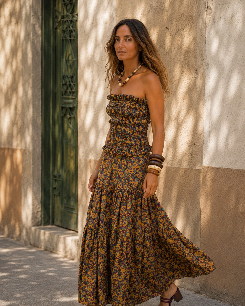 Modelo caminando con conjunto estampado en tonos mostaza, bordó y verde, con sandalias bordó y accesorios artesanales.