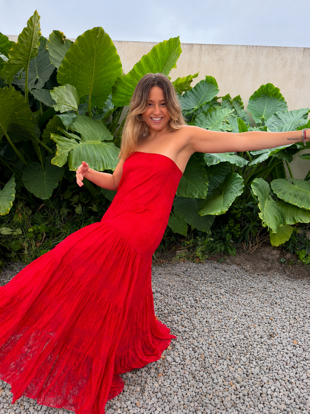 Modelo luciendo vestido largo strapless de encaje rojo con falda amplia y fruncida.