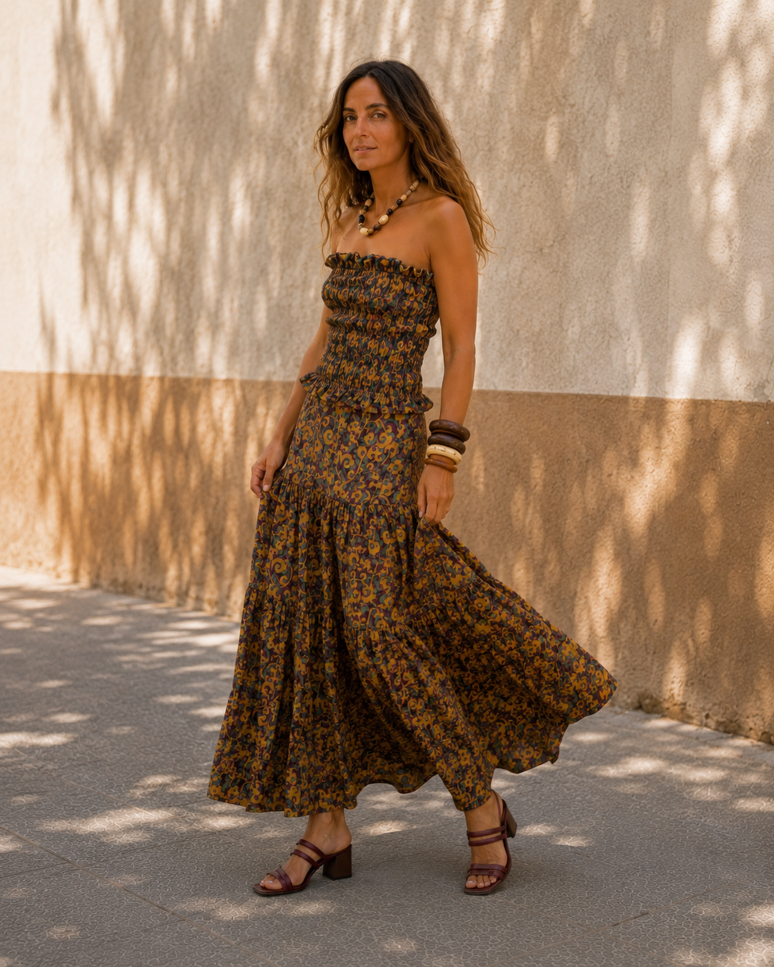 Modelo caminando con conjunto estampado en tonos mostaza, bordó y verde, con sandalias bordó y accesorios artesanales.