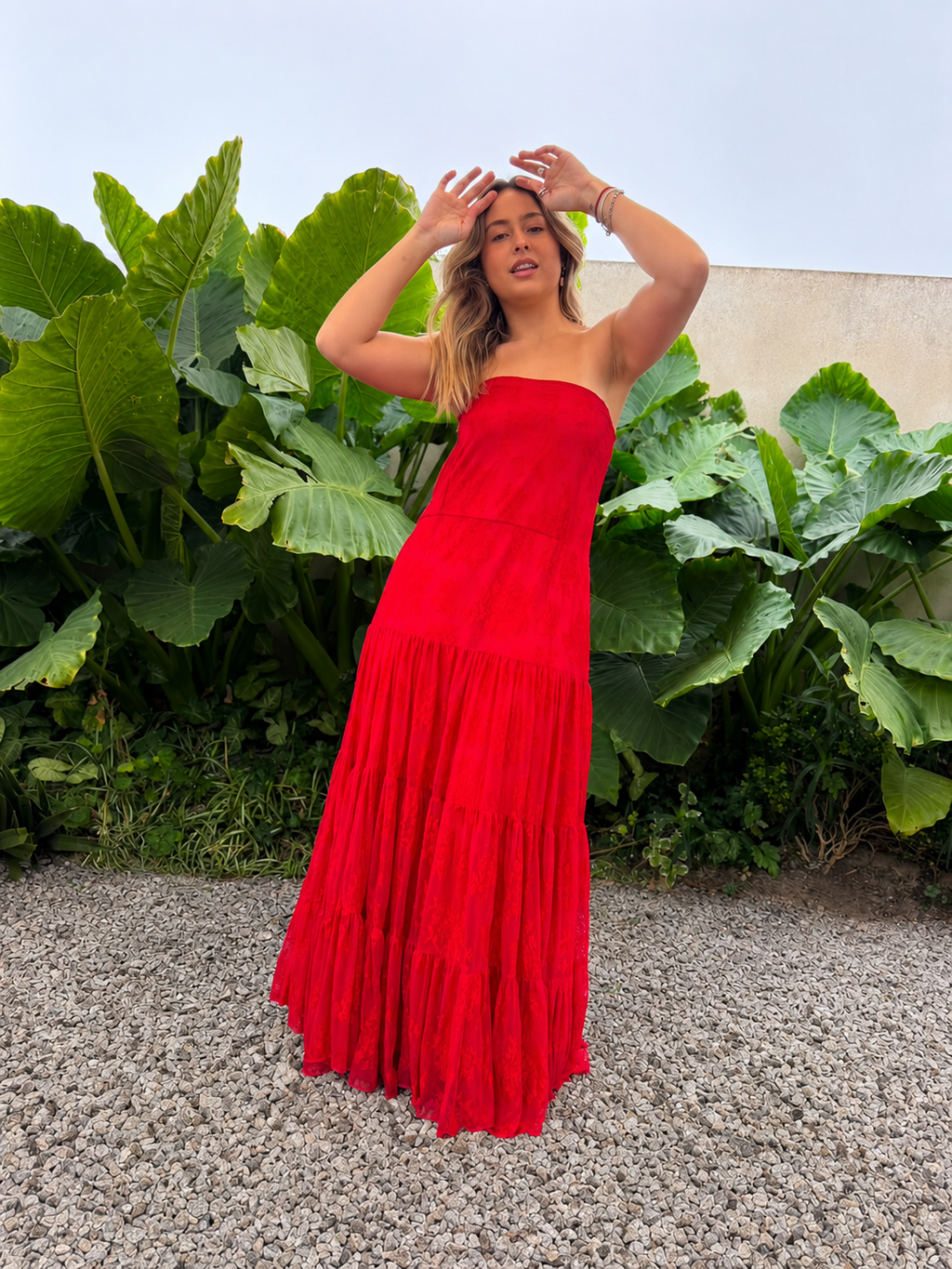 Modelo luciendo vestido largo strapless de encaje rojo con falda amplia y fruncida.