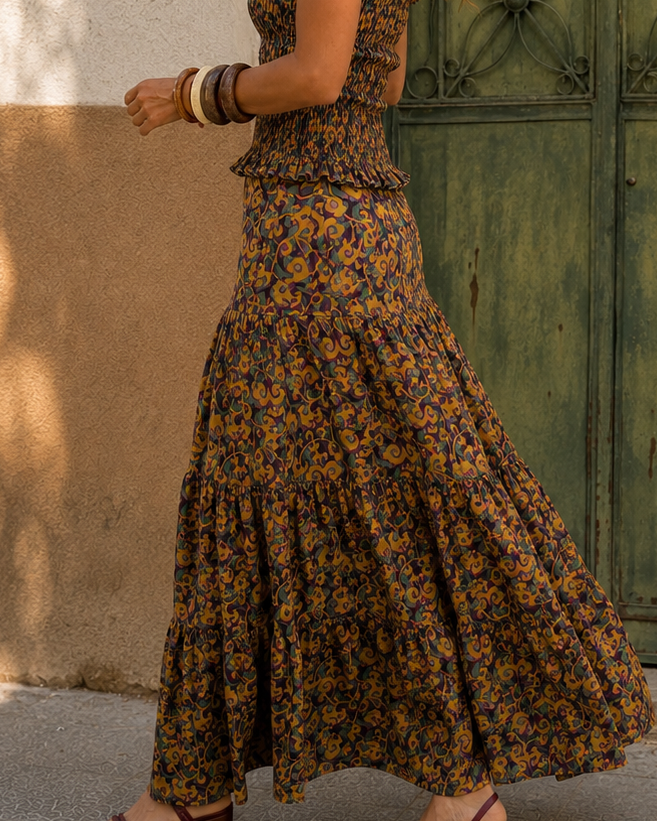 Modelo caminando con conjunto estampado en tonos mostaza, bordó y verde, con sandalias bordó y accesorios artesanales.