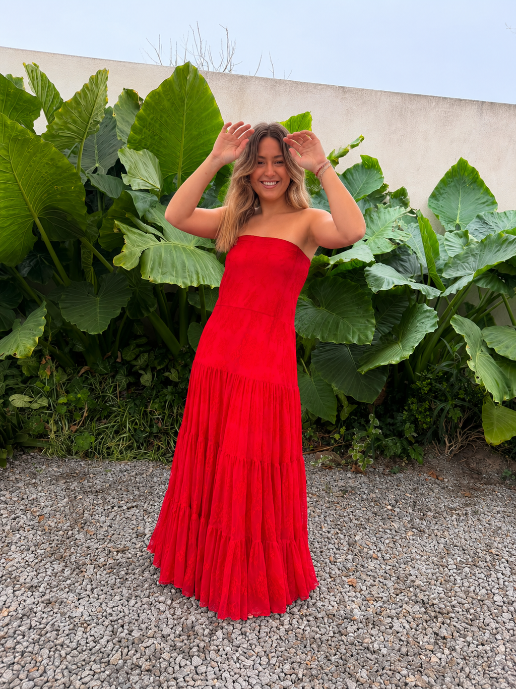 Modelo luciendo vestido largo strapless de encaje rojo con falda amplia y fruncida.